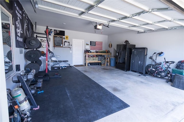 5803 SW Gentle Winds Ave, Bentonville, AR 72713 - garage featuring black refrigerator with ice dispenser, a garage door opener, and a workshop area