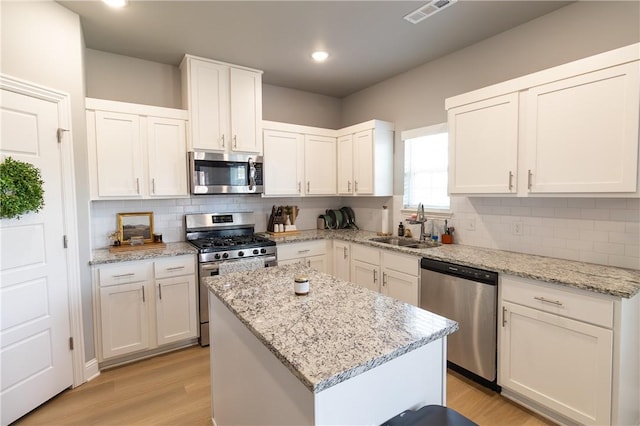 5803 SW Gentle Winds Ave, Bentonville, AR 72713 - kitchen with stainless steel appliances, a sink, light wood finished floors, a kitchen island, and recessed lighting