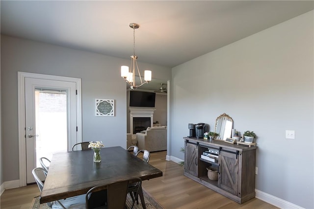 5803 SW Gentle Winds Ave, Bentonville, AR 72713 - dining room with a chandelier, light wood finished floors, baseboards, and a fireplace