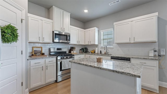5803 SW Gentle Winds Ave, Bentonville, AR 72713 - kitchen with appliances with stainless steel finishes, a sink, light wood finished floors, white cabinets, and recessed lighting