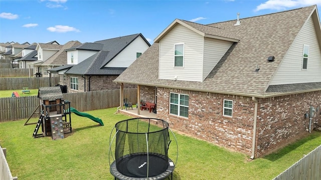 5803 SW Gentle Winds Ave, Bentonville, AR 72713 - rear view of house featuring brick siding, a trampoline, roof with shingles, a patio area, and a playground