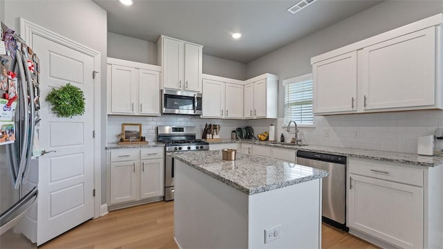 5803 SW Gentle Winds Ave, Bentonville, AR 72713 - kitchen featuring appliances with stainless steel finishes, a sink, white cabinetry, light wood finished floors, and recessed lighting