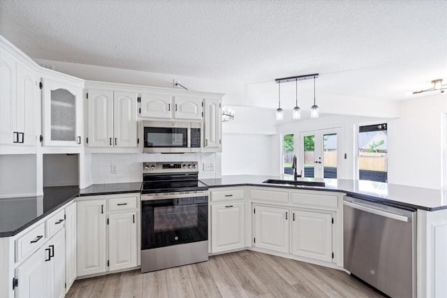 119 Elm St, Centerton, AR 72719 - kitchen with appliances with stainless steel finishes, a sink, a textured ceiling, dark countertops, and white cabinetry