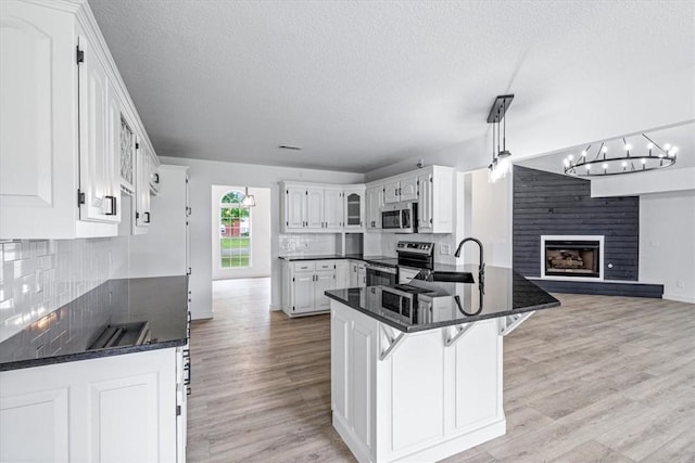 119 Elm St, Centerton, AR 72719 - kitchen featuring stainless steel appliances, light wood-style floors, a sink, decorative backsplash, and a textured ceiling