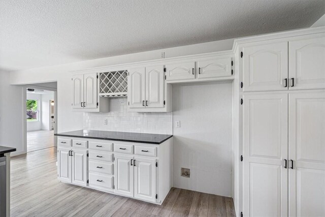 119 Elm St, Centerton, AR 72719 - kitchen with dark countertops, light wood-style flooring, white cabinetry, decorative backsplash, and a textured ceiling