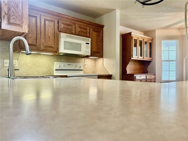 37 Retford Dr, Bella Vista, AR 72715 - kitchen with white microwave, range, decorative backsplash, a sink, and brown cabinetry