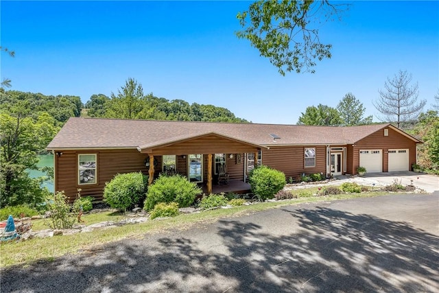 2895 County Road 116, Eureka Springs, AR 72631 - view of front facade featuring an attached garage, concrete driveway, roof with shingles, and covered porch