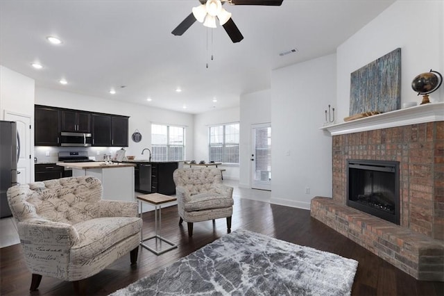 600 Gala Cir, Bentonville, AR 72712 - living room with a ceiling fan, recessed lighting, dark wood-style flooring, a brick fireplace, and baseboards