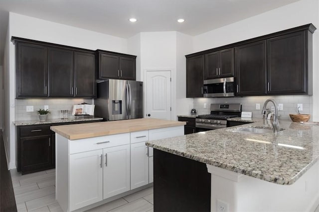 600 Gala Cir, Bentonville, AR 72712 - kitchen with stainless steel appliances, a sink, light stone counters, backsplash, and a kitchen island