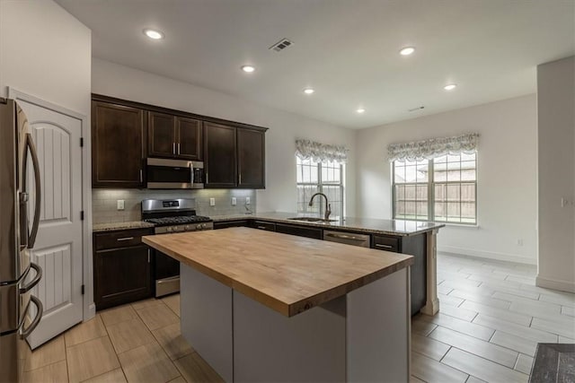 600 Gala Cir, Bentonville, AR 72712 - kitchen featuring butcher block counters, stainless steel appliances, a sink, a peninsula, and backsplash