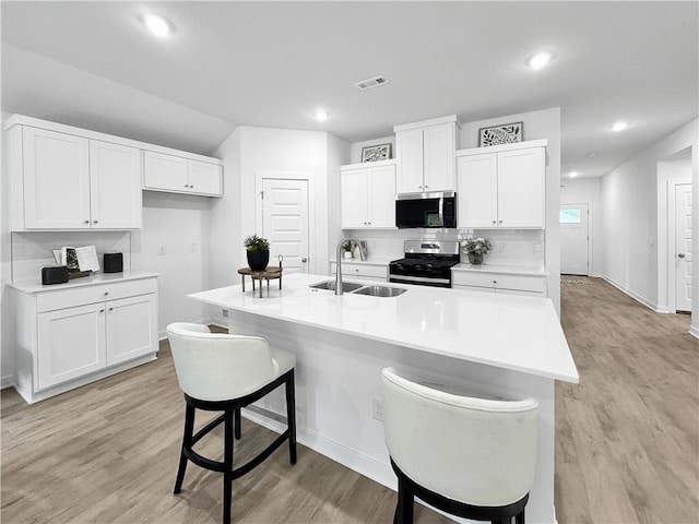1661 Ridgeview Dr, Springdale, AR 72762 - kitchen featuring stainless steel appliances, a sink, light wood-type flooring, a kitchen bar, and white cabinetry