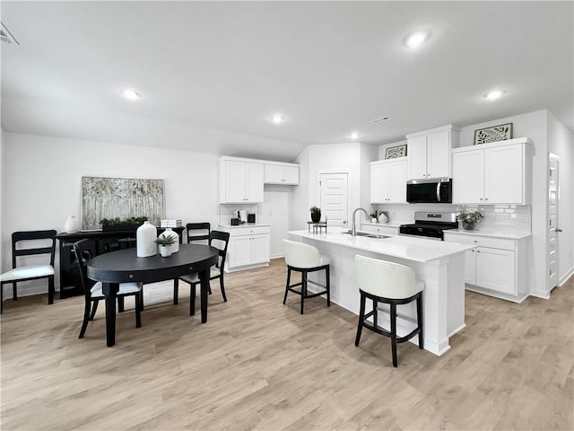 1661 Ridgeview Dr, Springdale, AR 72762 - kitchen featuring stainless steel appliances, a sink, a kitchen bar, light wood-style flooring, and light countertops