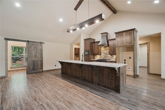 480124 E 1082nd Rd, Muldrow, OK 74948 - kitchen featuring wood finished floors, tasteful backsplash, premium range hood, a large island with sink, and beamed ceiling