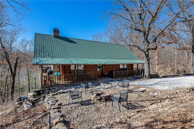 22283 N Log Cabin Dr, Sulphur Springs, AR 72768 - view of front of property featuring a chimney, an outdoor fire pit, covered porch, metal roof, and log siding