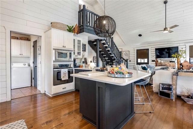 22283 N Log Cabin Dr, Sulphur Springs, AR 72768 - kitchen featuring washer / clothes dryer, appliances with stainless steel finishes, light countertops, high vaulted ceiling, and a kitchen breakfast bar