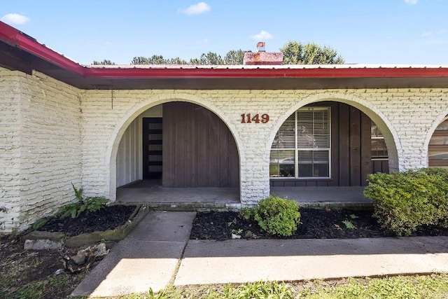 1149 Sunrise Ave, Springdale, AR 72764 - doorway to property featuring brick siding, metal roof, a chimney, and a porch