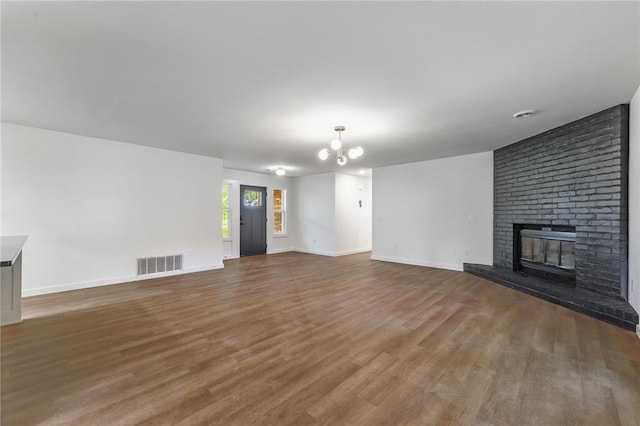 5479 Bob Mills Rd, Springdale, AR 72762 - unfurnished living room with wood finished floors, a chandelier, a brick fireplace, and baseboards