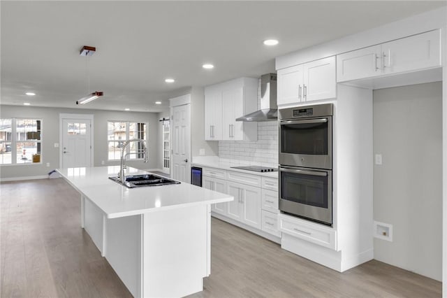 1115 Eicher Ave, Springdale, AR 72764 - kitchen with wall chimney exhaust hood, stainless steel double oven, a sink, black electric stovetop, and light wood-style flooring