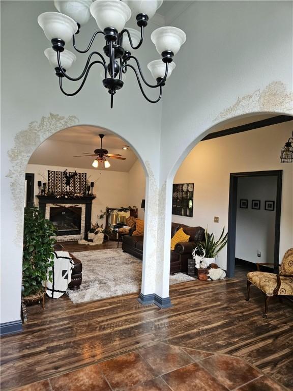 3 Rhonda Ln, Bella Vista, AR 72715 - living room featuring arched walkways, a chandelier, a ceiling fan, a fireplace, and wood finished floors