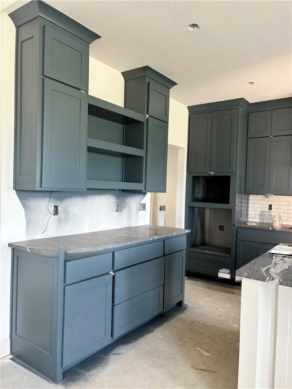841 Bellagiola Ave, Tontitown, AR 72762 - kitchen with backsplash, unfinished concrete floors, open shelves, and stone countertops
