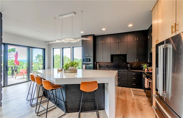 675 N Cliffside Dr, Fayetteville, AR 72701 - kitchen with stainless steel appliances, a breakfast bar area, light wood-style flooring, tasteful backsplash, and recessed lighting