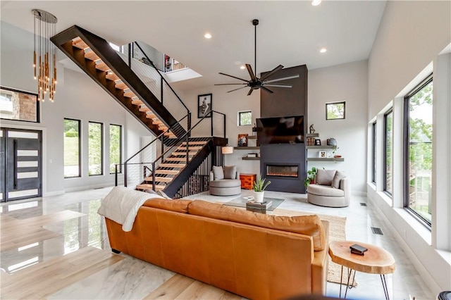 675 N Cliffside Dr, Fayetteville, AR 72701 - living area featuring plenty of natural light, a towering ceiling, stairway, a glass covered fireplace, and ceiling fan