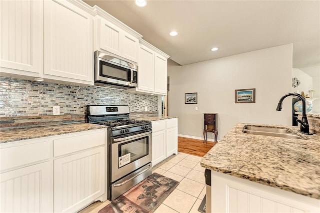 811 SW Pure Globe St, Bentonville, AR 72712 - kitchen featuring stainless steel appliances, a sink, tasteful backsplash, light tile patterned flooring, and white cabinets