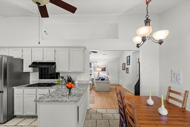 1110 Meadowlark Ln, Siloam Springs, AR 72761 - kitchen with under cabinet range hood, gas cooktop, a ceiling fan, a chandelier, and freestanding refrigerator
