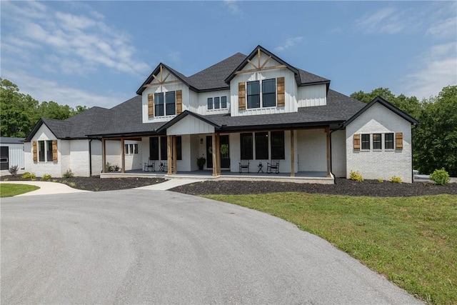 2762 Wilson Ln, Fayetteville, AR 72703 - modern inspired farmhouse featuring a porch, a front yard, roof with shingles, and brick siding