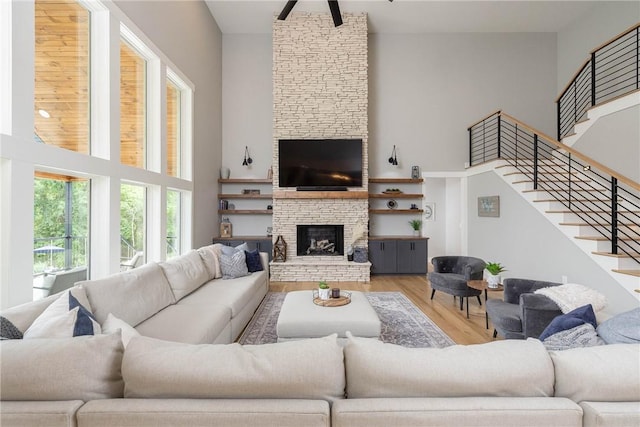 2762 Wilson Ln, Fayetteville, AR 72703 - living room featuring a high ceiling, healthy amount of natural light, wood finished floors, stairs, and a fireplace