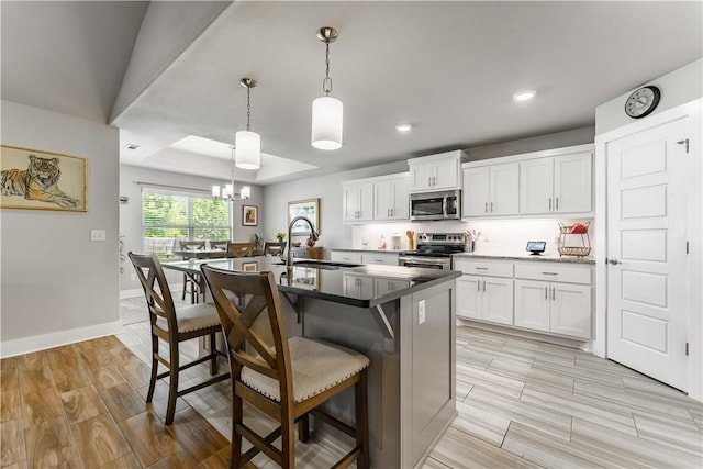 6 Briscoe Ln, Bella Vista, AR 72715 - kitchen featuring appliances with stainless steel finishes, a sink, a breakfast bar area, wood finish floors, and a center island with sink