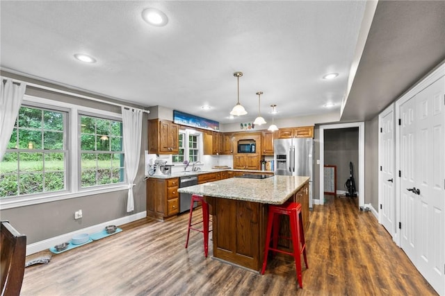 14090 Canal St, Rogers, AR 72758 - kitchen featuring stainless steel appliances, brown cabinetry, dark wood-type flooring, a kitchen breakfast bar, and a kitchen island