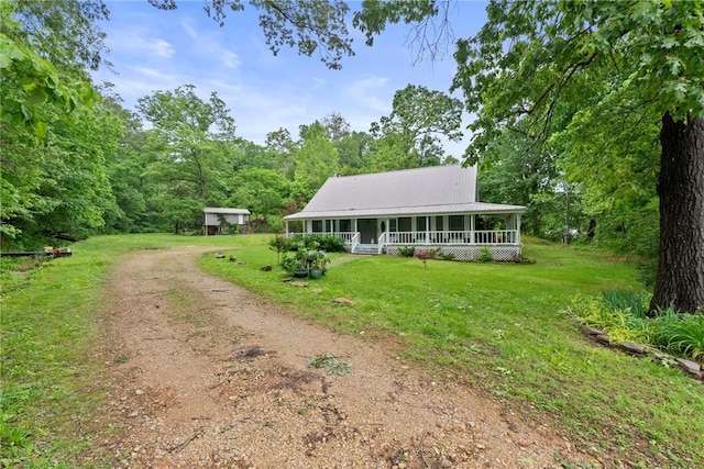 14090 Canal St, Rogers, AR 72758 - farmhouse inspired home with a porch, dirt driveway, a front lawn, a wooded view, and metal roof