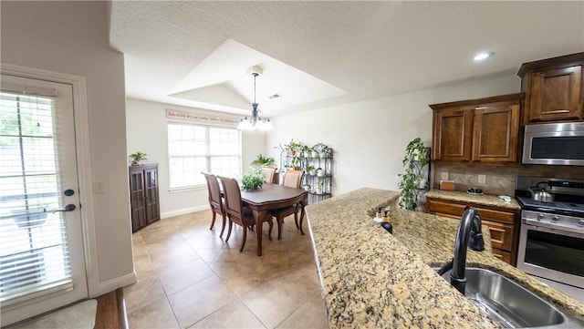 1011 Harvest St, Centerton, AR 72719 - kitchen with stainless steel appliances, a chandelier, light stone countertops, decorative light fixtures, and backsplash
