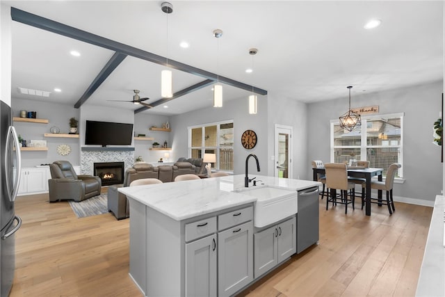 1408 SW Breeze Ct, Bentonville, AR 72713 - kitchen featuring stainless steel appliances, a sink, ceiling fan, light wood-style floors, and a tile fireplace