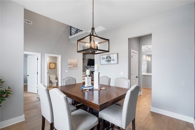 1408 SW Breeze Ct, Bentonville, AR 72713 - dining area featuring light wood finished floors, a chandelier, baseboards, and stairs