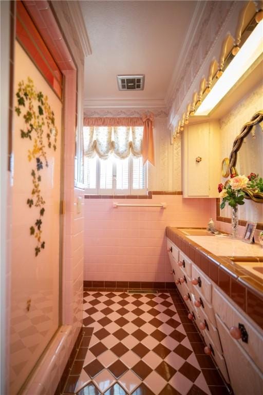 1617 Ranch Dr, Springdale, AR 72762 - bathroom featuring tile patterned floors, ornamental molding, double vanity, a stall shower, and tile walls