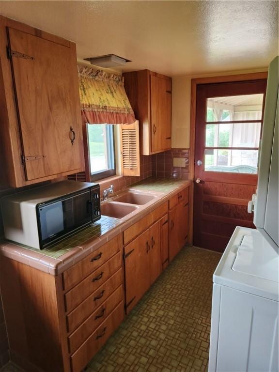 1617 Ranch Dr, Springdale, AR 72762 - kitchen with tile countertops, black microwave, a sink, washer / dryer, and a textured ceiling