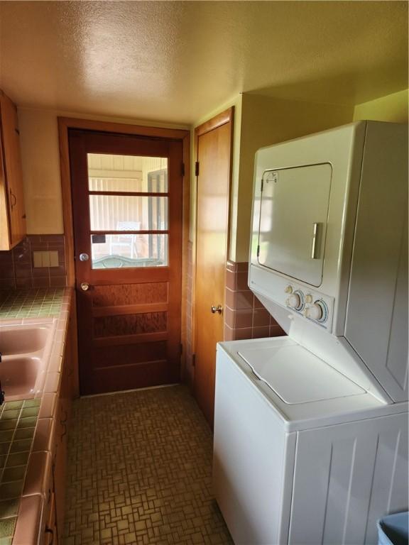 1617 Ranch Dr, Springdale, AR 72762 - washroom featuring stacked washer and clothes dryer and a textured ceiling