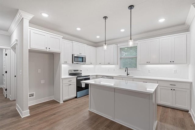 7 Mcginnis Ln, Bella Vista, AR 72715 - kitchen featuring stainless steel appliances, ornamental molding, wood finished floors, white cabinetry, and tasteful backsplash