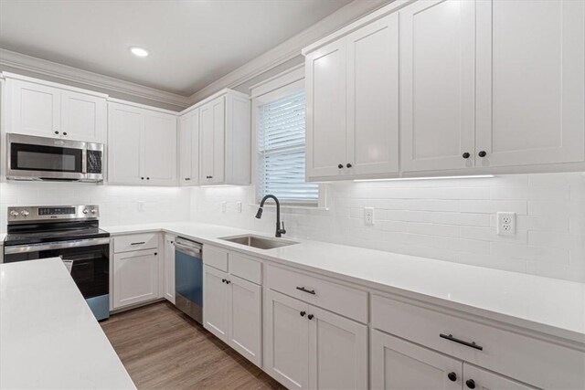 7 Mcginnis Ln, Bella Vista, AR 72715 - kitchen with stainless steel appliances, a sink, light countertops, white cabinets, and crown molding