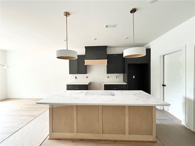 1 Consett Ln, Bella Vista, AR 72714 - kitchen with tasteful backsplash, a kitchen island, light stone counters, dark cabinetry, and decorative light fixtures