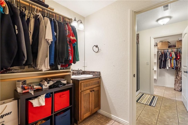 14453 Merritt Dr, Pea Ridge, AR 72751 - full bath with tile patterned floors, vanity, a spacious closet, a textured wall, and baseboards