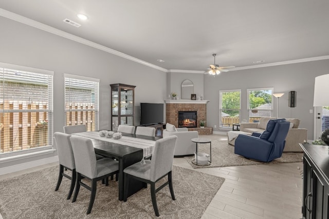1431 Ari Ave, Centerton, AR 72719 - dining space with crown molding, a brick fireplace, a ceiling fan, light wood-style floors, and baseboards