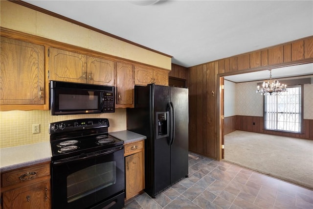 711 W 18th Ter, Russellville, AR 72801 - kitchen featuring black appliances, a chandelier, wood walls, brown cabinets, and dark colored carpet