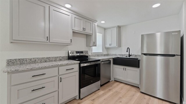1580 Jones Ln, Pea Ridge, AR 72751 - kitchen featuring appliances with stainless steel finishes, a sink, light wood-style floors, light stone countertops, and recessed lighting