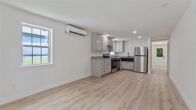 1580 Jones Ln, Pea Ridge, AR 72751 - kitchen with stainless steel appliances, a wall mounted AC, light wood-type flooring, a sink, and baseboards