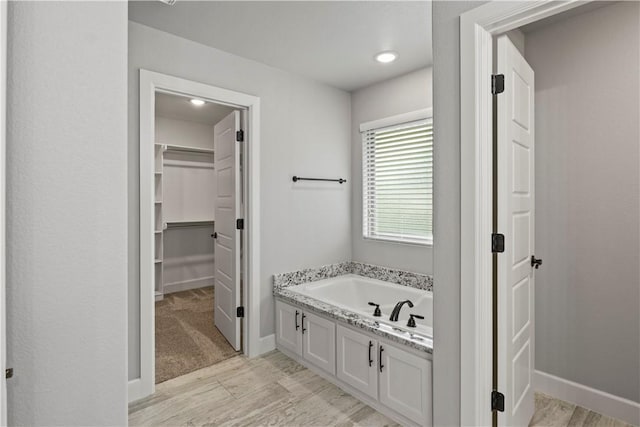 1440 Amber Way, Centerton, AR 72719 - bathroom with wood finished floors, a garden tub, a walk in closet, baseboards, and recessed lighting