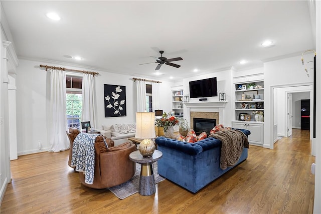 306 Osage Ct, Russellville, AR 72802 - living room featuring a glass covered fireplace, a ceiling fan, light wood-type flooring, recessed lighting, and built in shelves