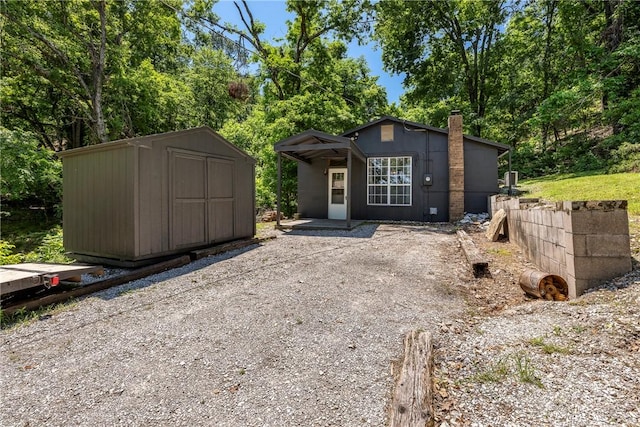 19051 Pinecrest Ln, Rogers, AR 72756 - view of front of house featuring a storage shed, a chimney, and view of wooded area